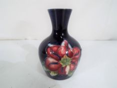 Moorcroft Pottery - a small vase by Moorcroft Pottery in the Clematis pattern on a blue ground,