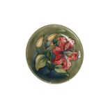 A MOORCROFT POTTERY PLATE, tubelined and painted with hibiscus against a green ground,