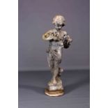 A COMPOSITION WEATHERED FIGURE, modelled holding a nest of birds.