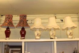 Three pottery table lamps and shades decorated with peacocks and pair of burgundy pottery lamps