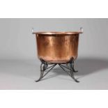 A LARGE POLISHED COPPER CHEESE KETTLE, with wrought iron stand. 67.