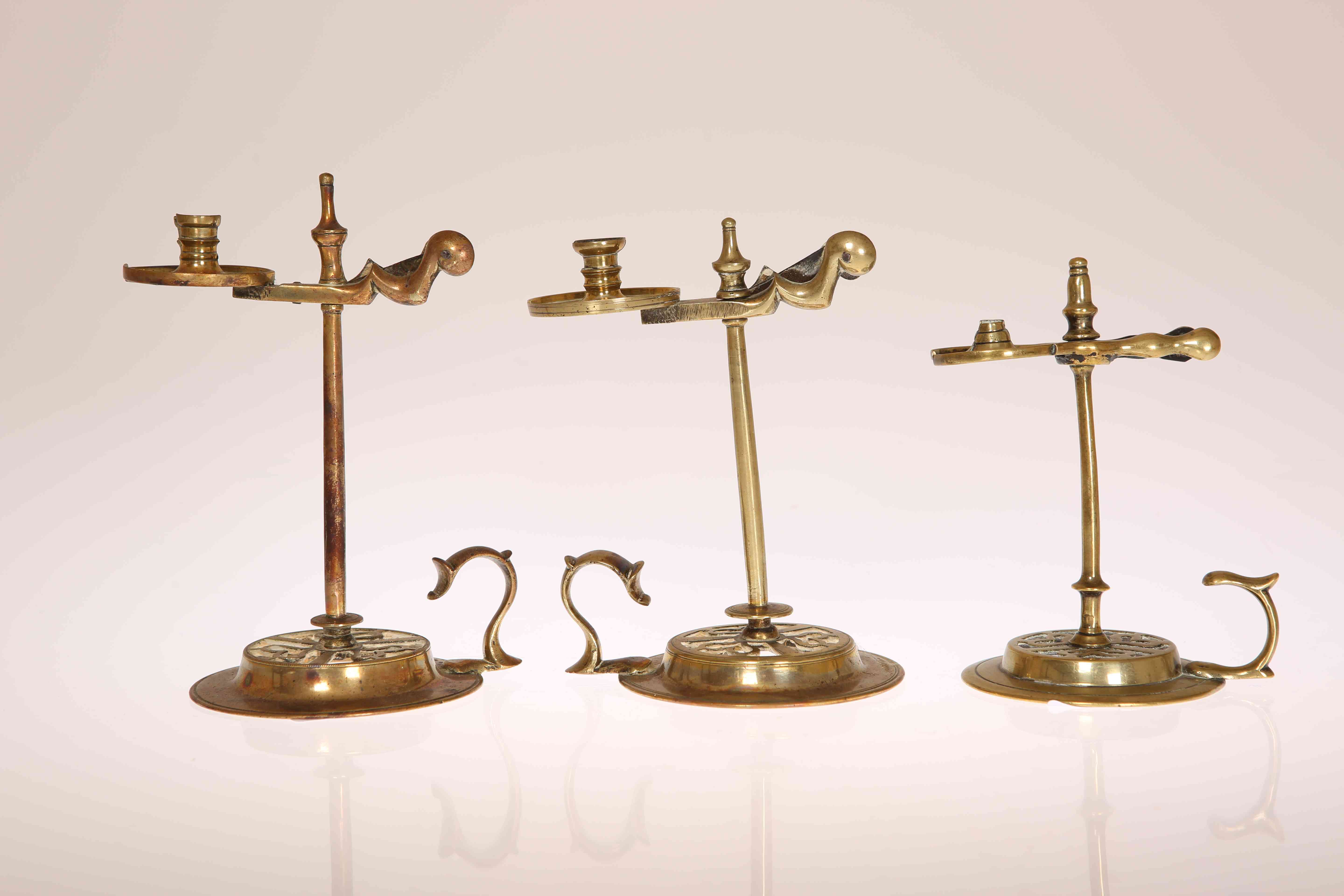 THREE GEORGE III BRASS WAX JACKS, circa 1775, each of characteristic form with urn finial,