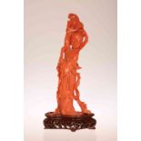A CHINESE CARVED RED CORAL FIGURE OF A YOUNG WOMAN, or female deity, her right arm upraised,