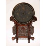 A LARGE CHINESE BRONZE MIRROR IN ARCHAIC STYLE ON A CARVED HARDWOOD STAND,