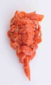 A CARVED CORAL PENDANT BROOCH, elaborately carved to depict a woman's face amongst foliage,