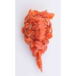 A CARVED CORAL PENDANT BROOCH, elaborately carved to depict a woman's face amongst foliage,