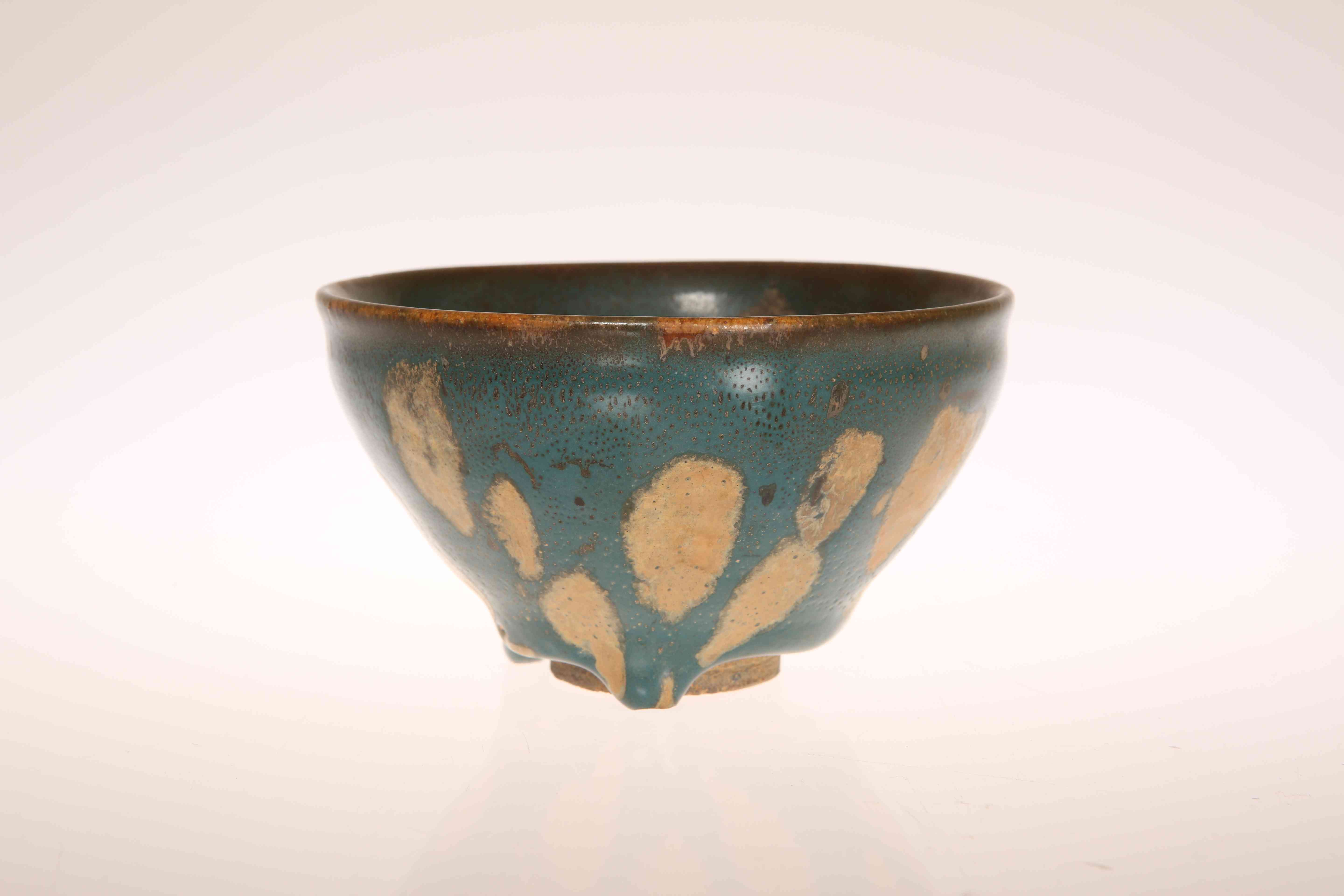 A CHINESE GREEN GLAZED POTTERY BOWL IN THE SUNG STYLE, mottled glazed with unglazed foot.