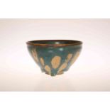 A CHINESE GREEN GLAZED POTTERY BOWL IN THE SUNG STYLE, mottled glazed with unglazed foot.