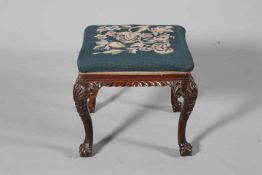 A 19TH CENTURY CARVED MAHOGANY AND NEEDLEWORK STOOL, with ball and claw feet.