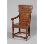 A 17TH CENTURY STYLE CARVED OAK WAINSCOT CHAIR, with planked seat and scroll carved crest.