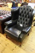 Deep buttoned and brass studded leather wing easy chair