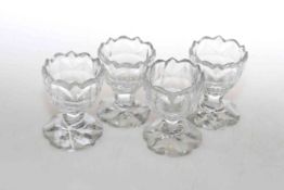 A set of four cut-glass salts, circa 1800, each with scalloped rim above a panelled body,