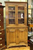 Period style oak cabinet bookcase having two glazed panel doors above a base of two fielded panel
