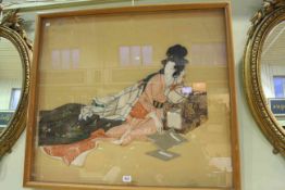 Framed and glazed fabric of an Oriental lady reclining on a book stand