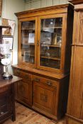 Late Victorian oak cabinet bookcase having two glazed panel doors above two drawers with two carved