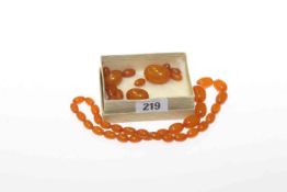 Amber coloured bead necklace and loose beads,