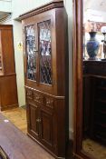 Bespoke oak double corner cabinet having two leaded glazed doors above three drawers with two