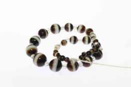 Banded onyx and rock crystal necklace, of thirty one graduating onyx beads on bolt ring clasp,