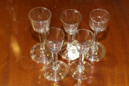 Collection of four folded foot wine glasses and a fifth with a plain foot,