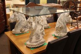 Glass topped low centre table mounted on four horses heads