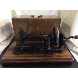 A vintage hand sewing machine in inlaid mahogany case