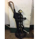 A cast iron d-shaped stick stand containing walking stick and umbrella