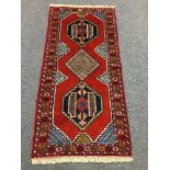 A fringed Persian rug on red ground,