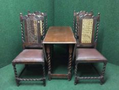 An oak drop leaf table and four carved oak dining chairs with bergere panels