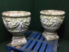 A large pair of stone classical garden planters with cherub decoration on stands
