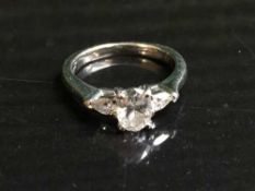 A platinum and diamond set ring, the central oval cut stone in four claw settting,