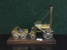 A brass model of Stephenson's Rocket on wooden plinth