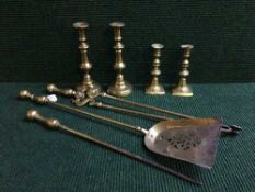 A three piece brass companion set together with two pairs of brass candleticks