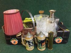 A box of copper jam pan, brass table lamp, beer steins, decanters, place mats,