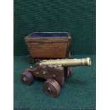 A brass cannon on wooden trolley and a sewing box modelled as a wooden cart