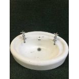 A mid 20th century oval wash basin with taps