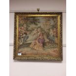 A gilt framed tapestry depicting figures by a wall