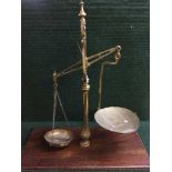 A set of antique brass balance scales mounted on mahogany plinth
