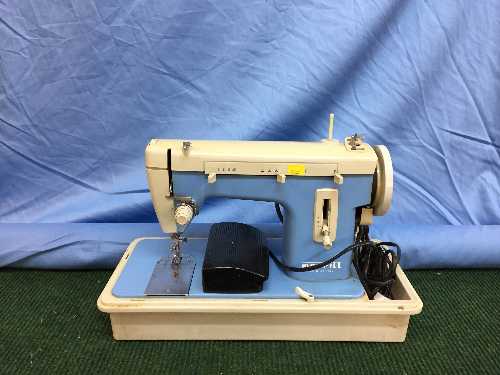 A Merit cased electric sewing machine together with a roll of material