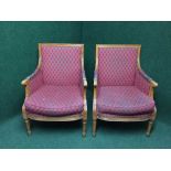 A pair of Victorian style armchairs upholstered in red fabric on reeded legs