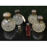 A collection of silver and cut glass scent bottles