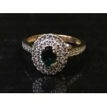 A diamond cluster ring with green central stone,