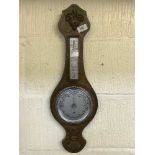 A carved oak aneroid barometer/thermometer