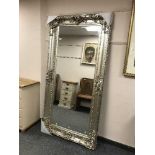 A large bevelled mirror in ornate silvered frame