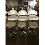 A set of three white leather swivel bar chairs on chrome bases and three swivel bar stools