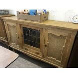 A continental oak triple door sideboard with leaded glass panel