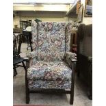 A wing backed armchair upholstered in floral buttoned fabric