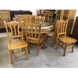 A circular pine pedestal dining table with plate glass top and six chairs