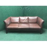 A wood framed brown leather three seater settee together with matching two seater settee