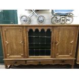 A continental oak triple door sideboard with leaded glass panel