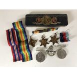 A tin of four WW II medals, some with ribbons, cap badge.